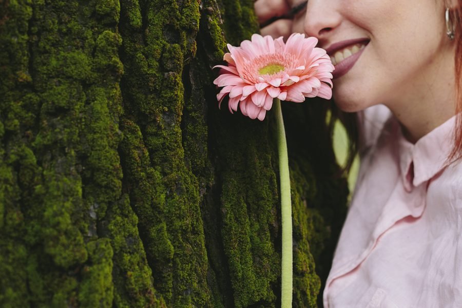 Imagen de Mujer oliendo flor en tronco de arbol